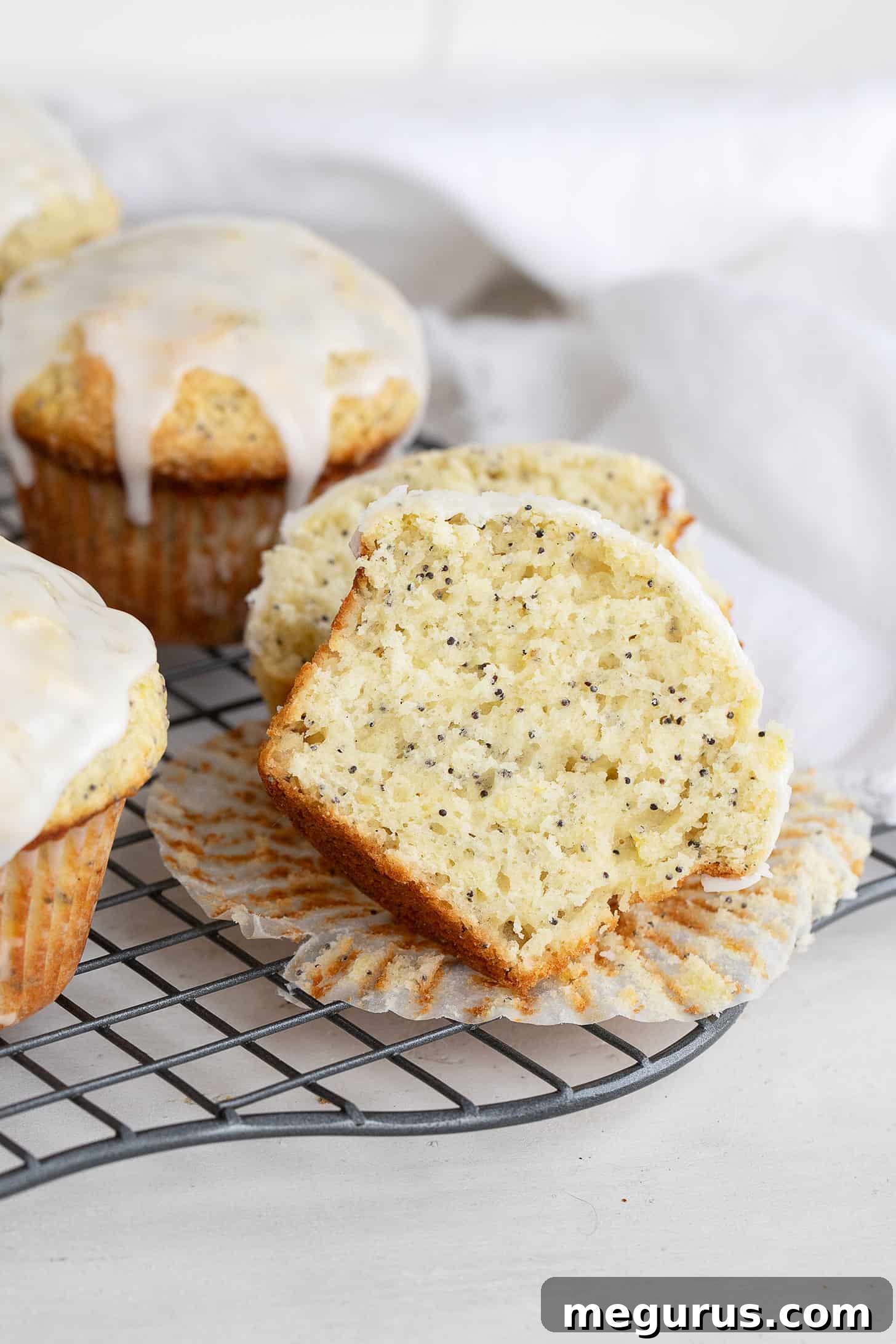 Close-up of freshly glazed lemon poppy seed muffins on a cooling rack, showcasing the tender crumb.