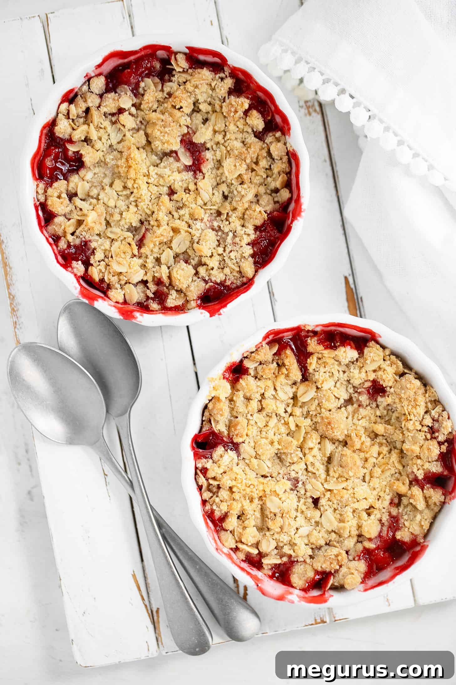 A beautifully baked strawberry crisp, golden and bubbly, with a scoop of vanilla ice cream melting on top.