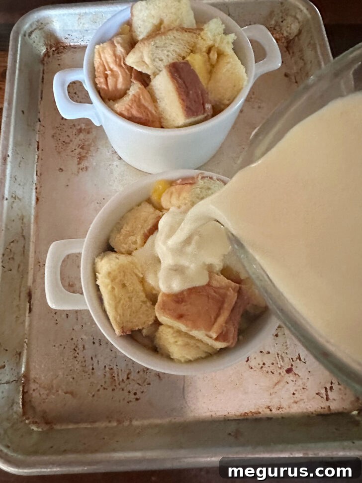 Rich custard mixture being poured over the bread and peach mixture in ramekins
