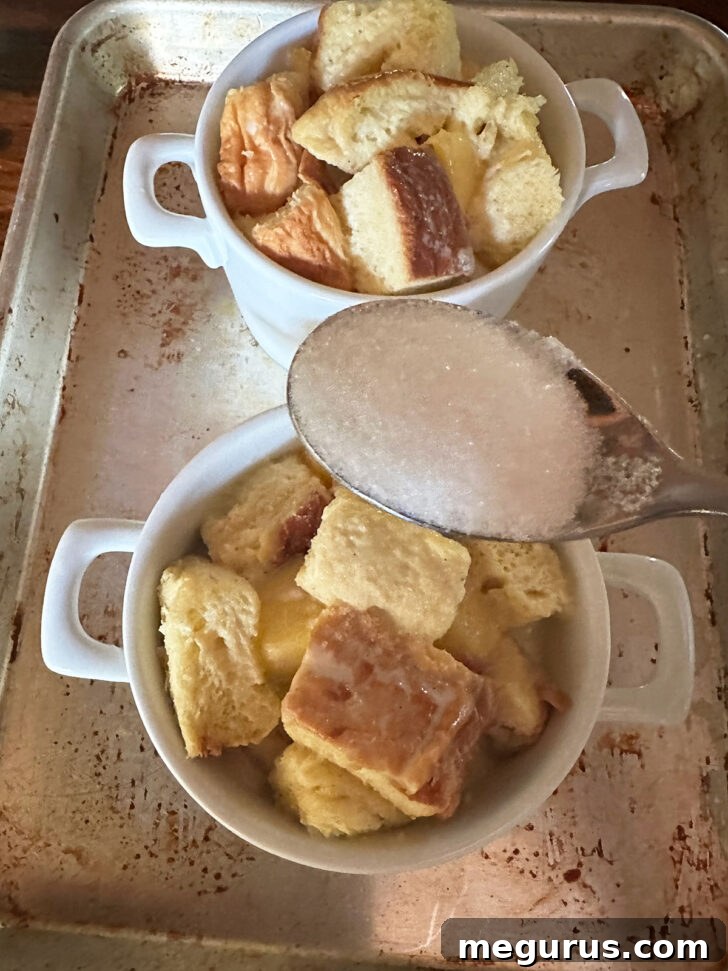 White sugar being sprinkled on top of peach bread puddings before baking for a crispy crust