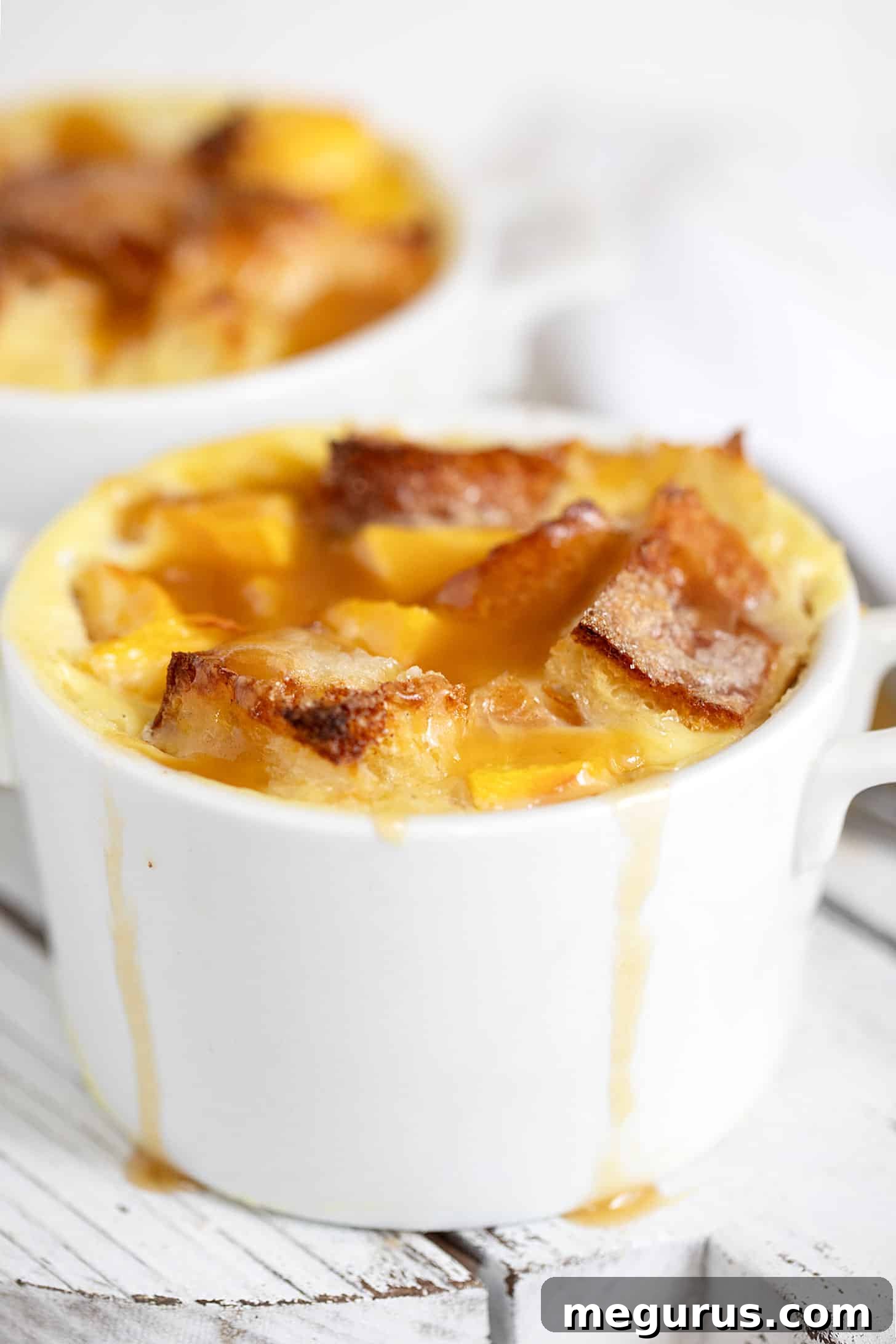 Close-up of peach bread pudding in ramekins, ready to serve with brown sugar sauce