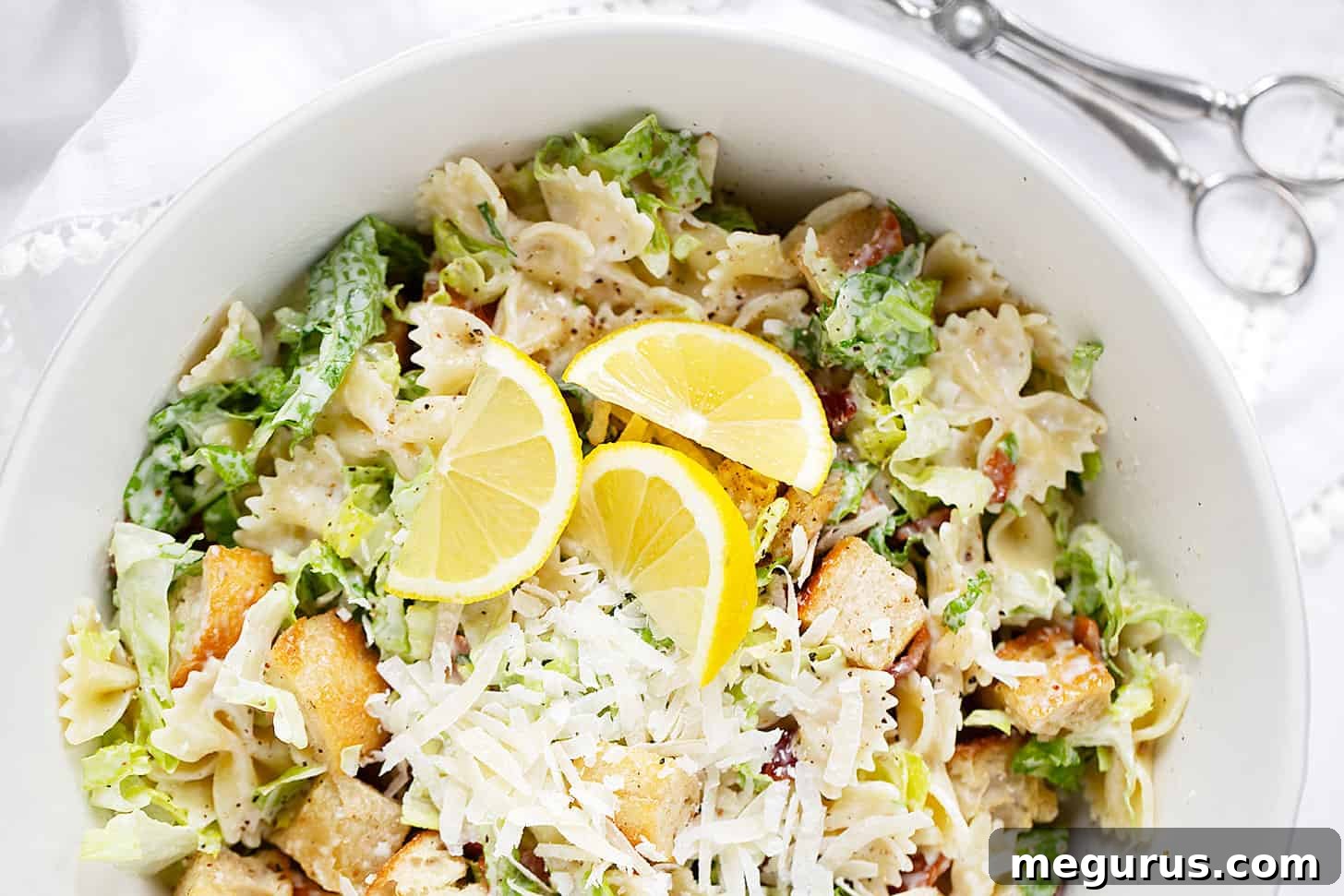 A vibrant Caesar pasta salad artfully arranged in a large serving bowl, showcasing bowtie pasta, crisp romaine, golden croutons, and crunchy bacon bits, all coated in a rich, creamy dressing.