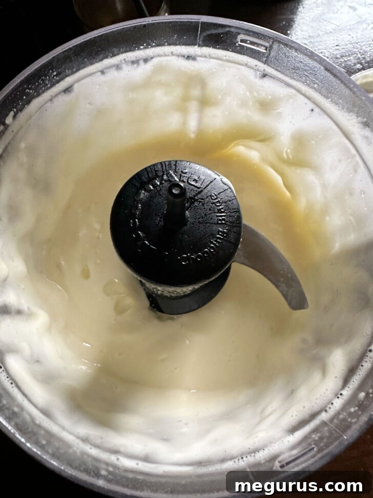 The perfectly emulsified, thick, and creamy Caesar salad dressing ready in the food processor, after all ingredients have been incorporated.
