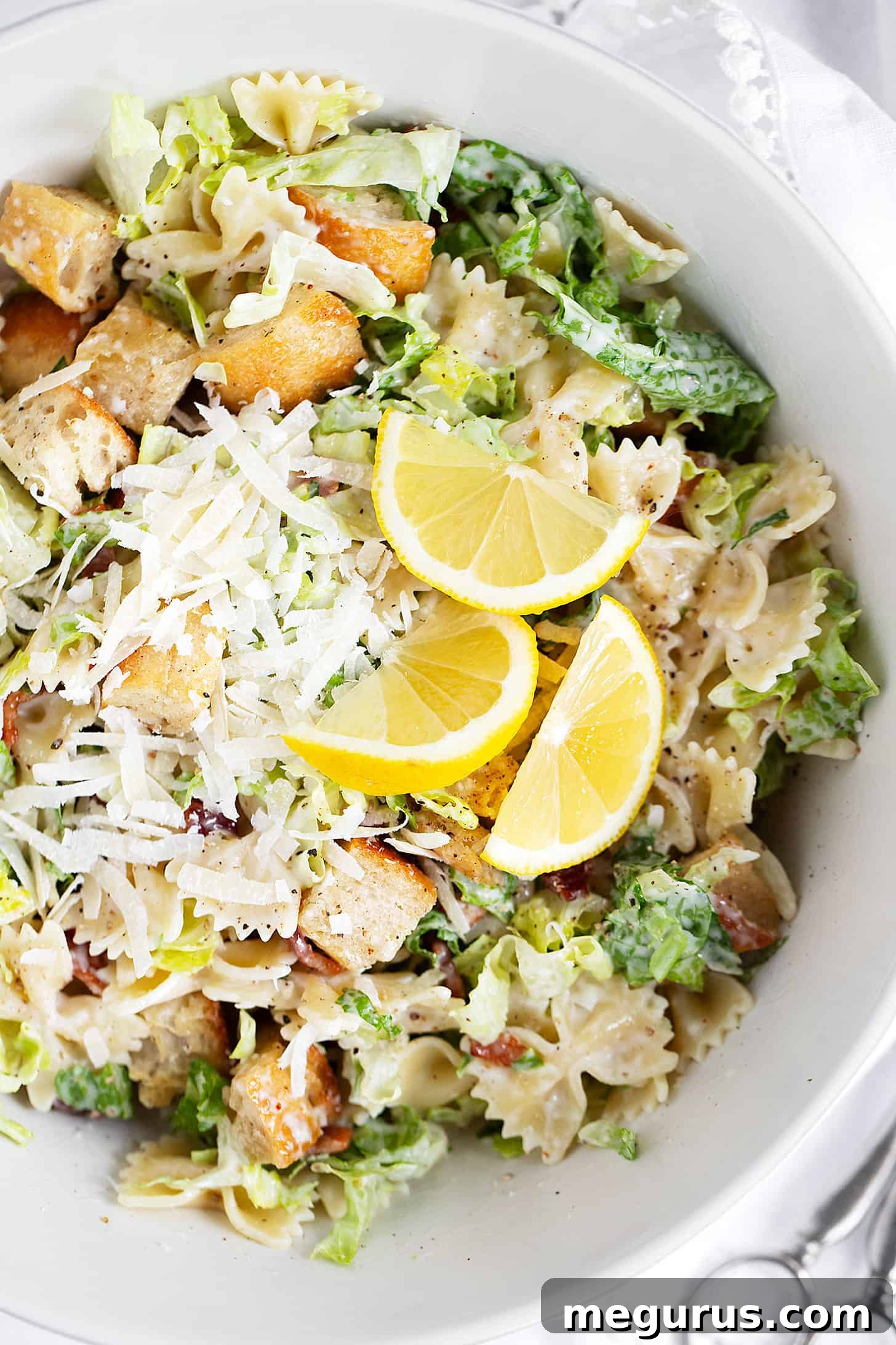 A close-up shot of the finished Caesar pasta salad in a beautiful ceramic bowl, ready for serving, highlighting the texture and freshness.