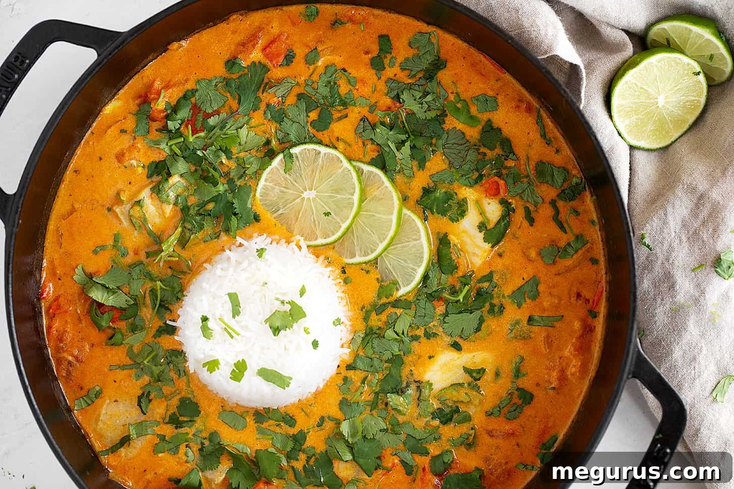 A steaming skillet of rich coconut fish curry, served alongside fluffy white rice.
