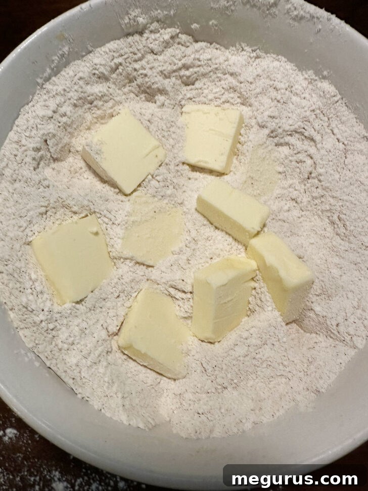 Cold, cubed butter being added to the dry crumb mixture, ready to be rubbed in.