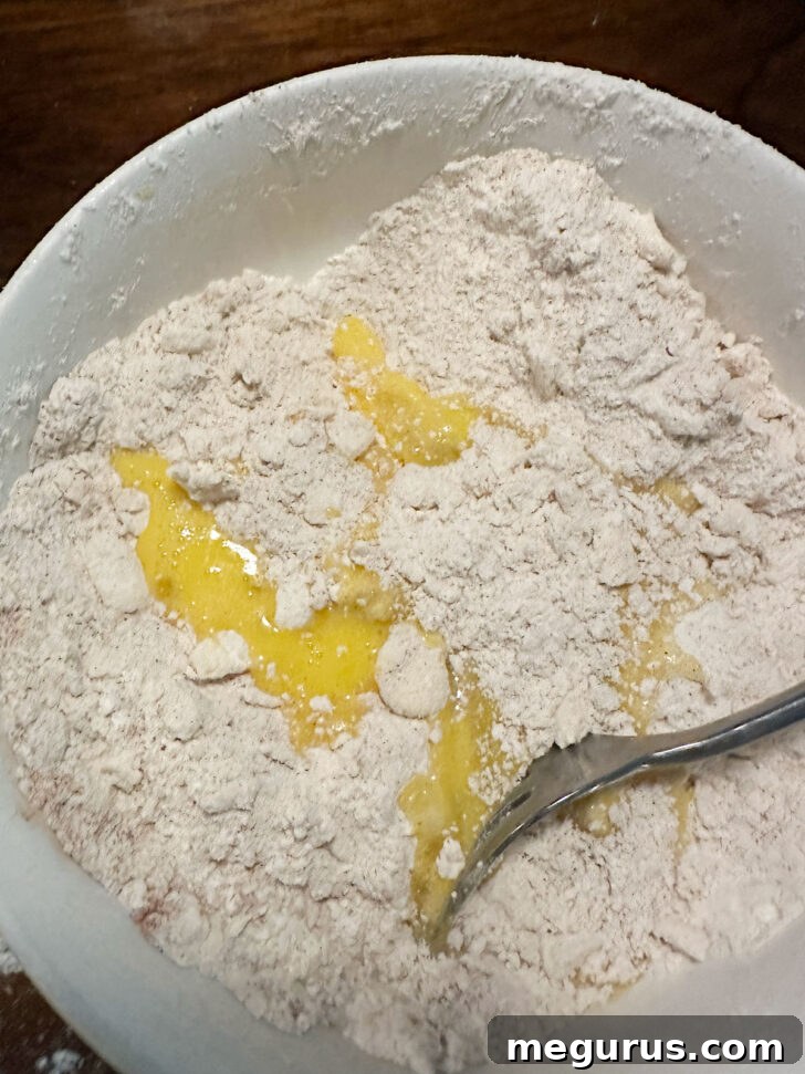 Beaten egg being stirred into the crumb mixture to bind it together.