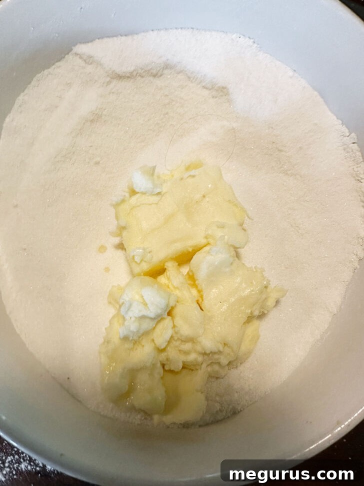 Softened butter being added to the dry filling ingredients and pressed with a fork until crumbly.