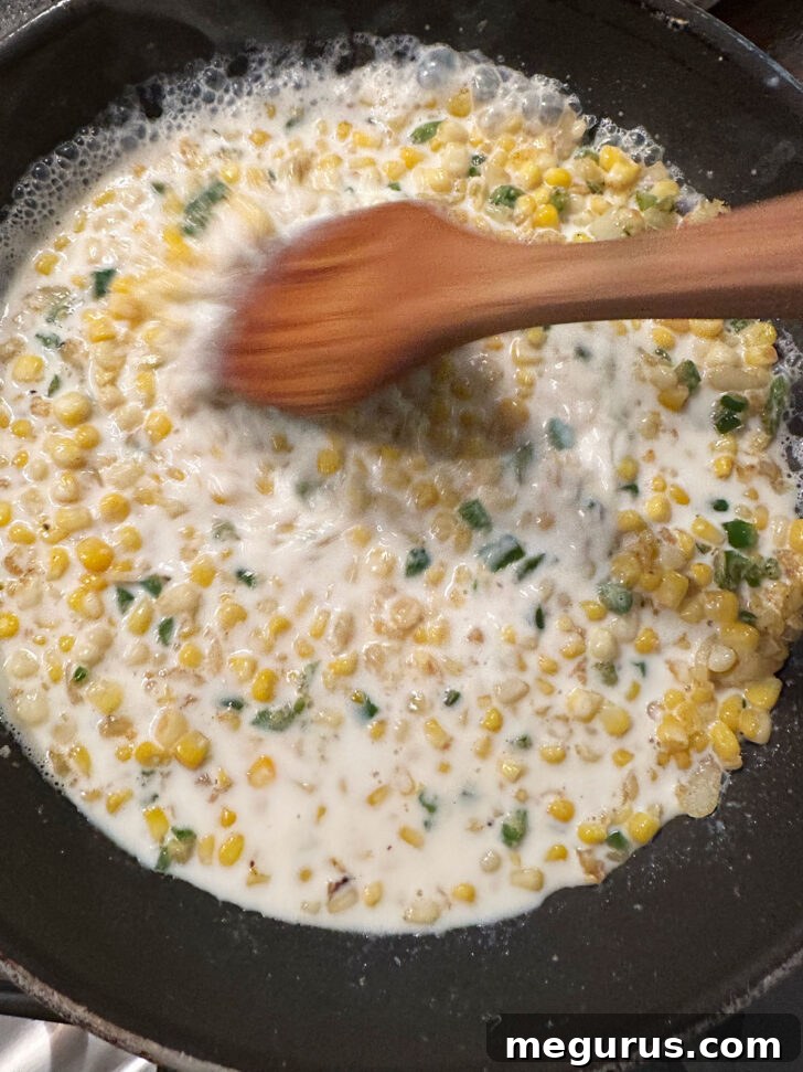 Milk being gradually stirred into the corn, jalapeño, and onion mixture in a skillet.