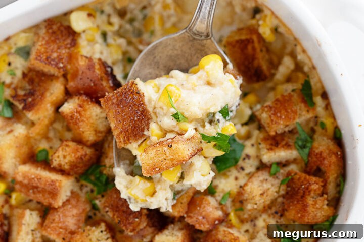 Scalloped corn casserole in baking dish with spoon, ready to be served.