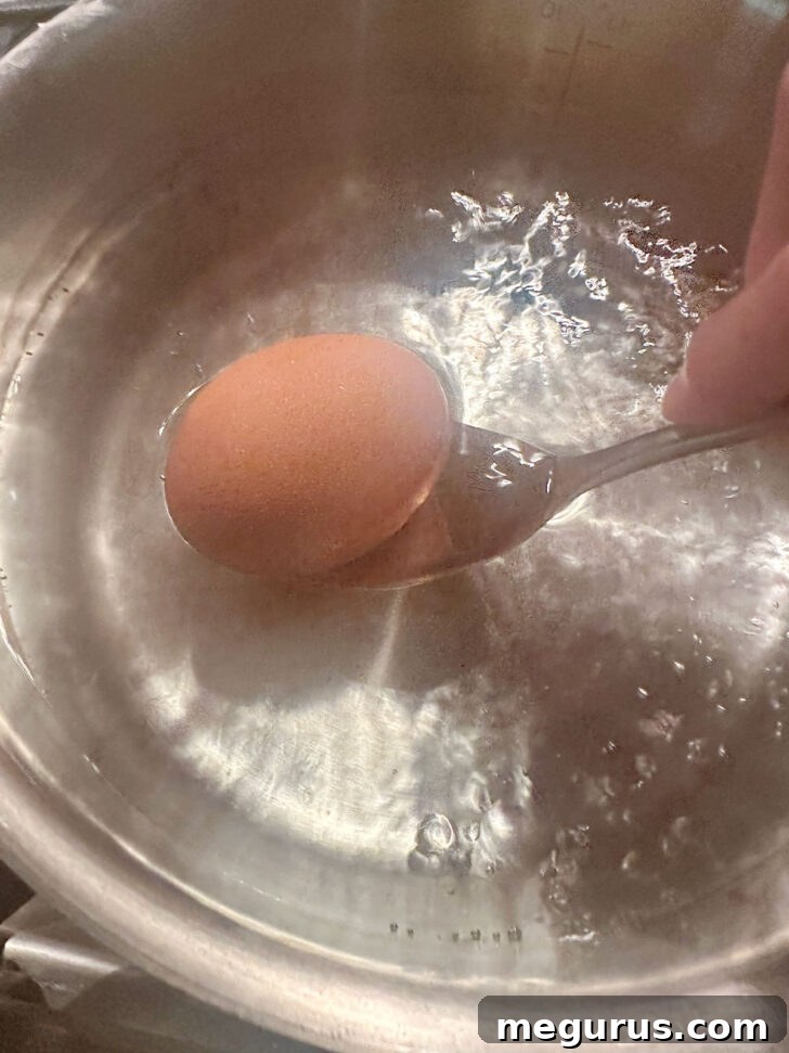 Lowering egg into boiling water with a spoon.