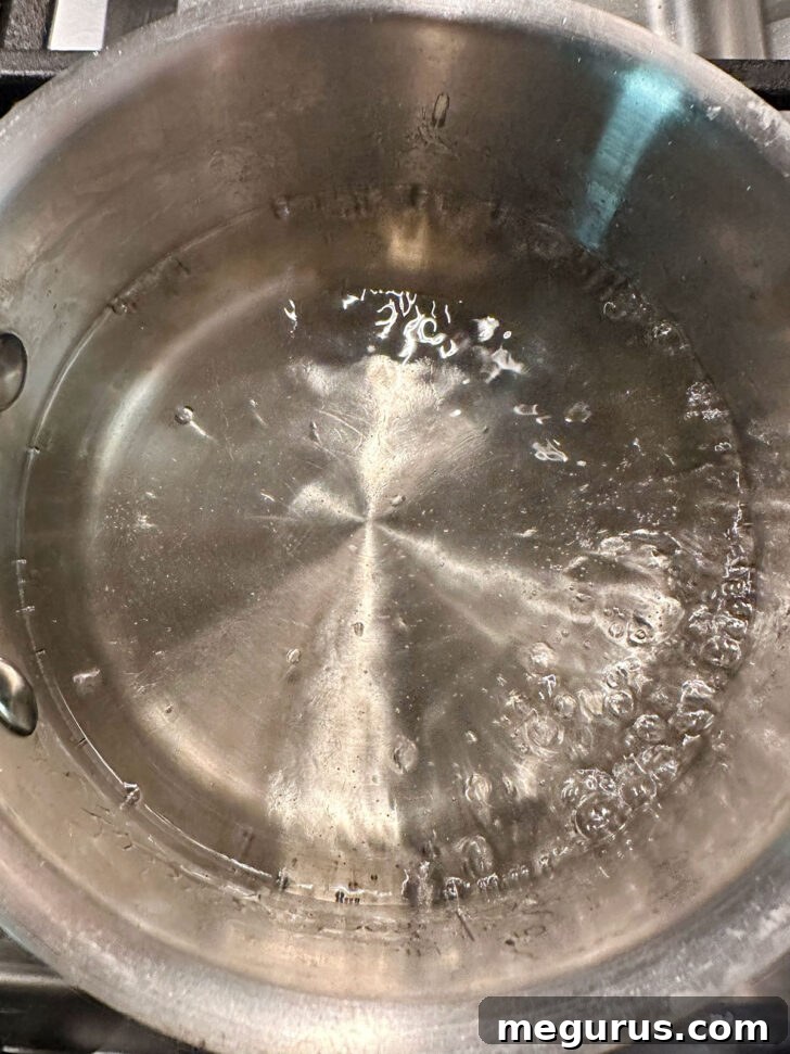 Water and white sugar are combined in a small saucepan over heat, beginning the vanilla simple syrup process.