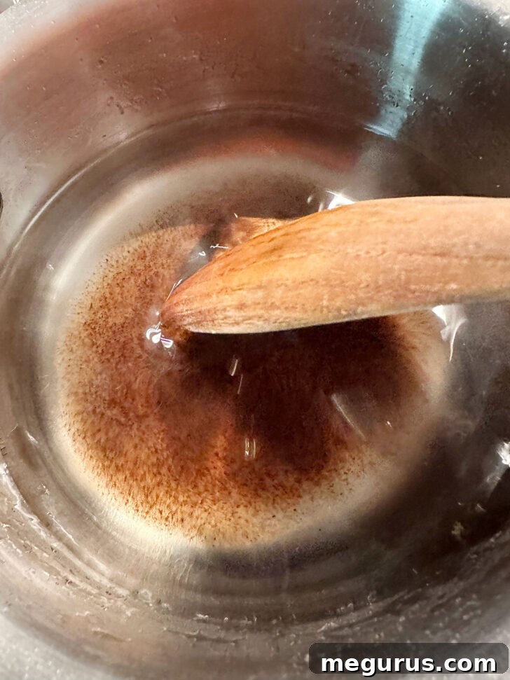 The vanilla extract is stirred into the sugar syrup after it has been removed from the heat, infusing the mixture with flavor.