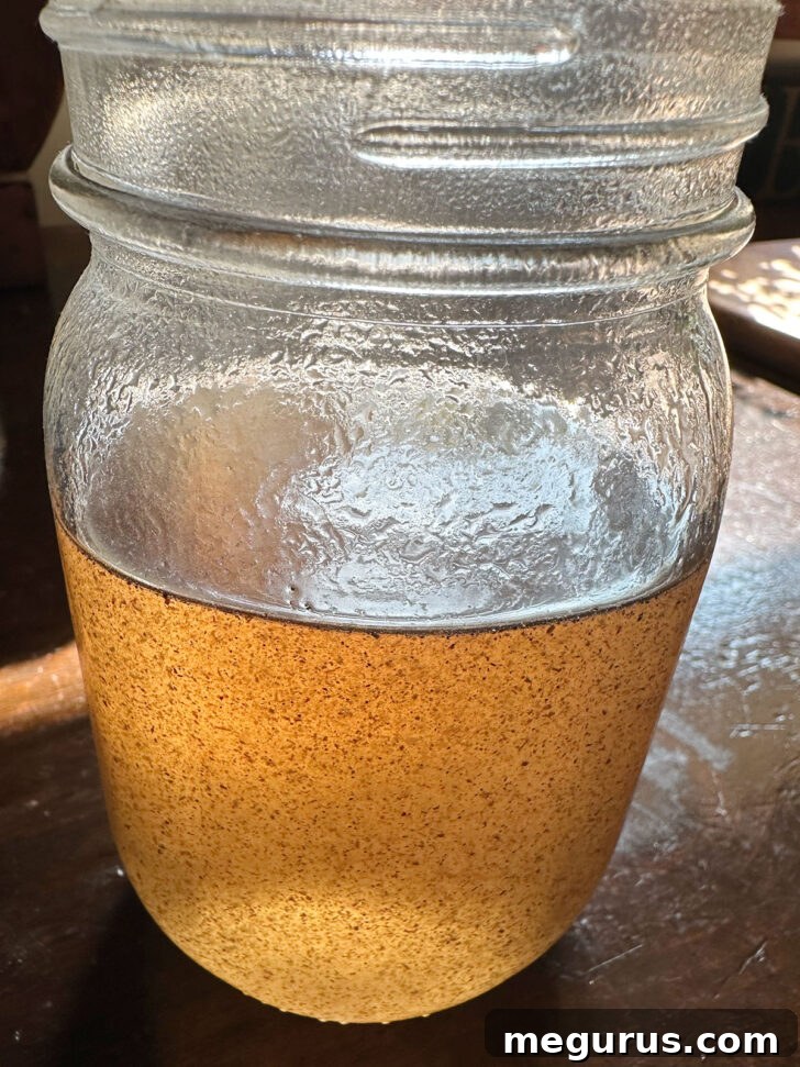 The finished vanilla simple syrup is carefully poured into a glass jar for cooling and storage in the refrigerator.