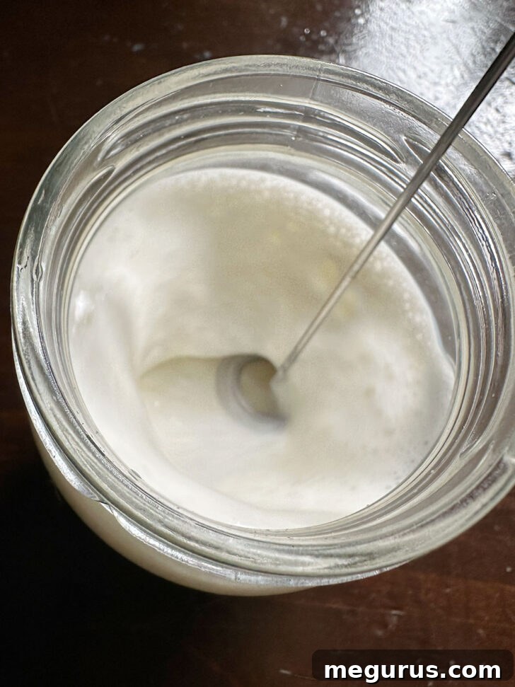 Close-up of perfectly frothed vanilla sweet cream cold foam in a jar, showing its thick, airy texture.
