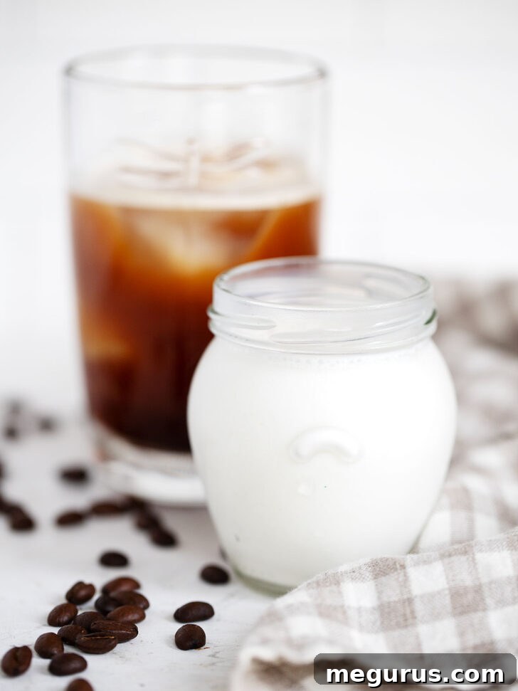The frothed vanilla sweet cream being poured over a glass of iced cold brew coffee, ready to be enjoyed.