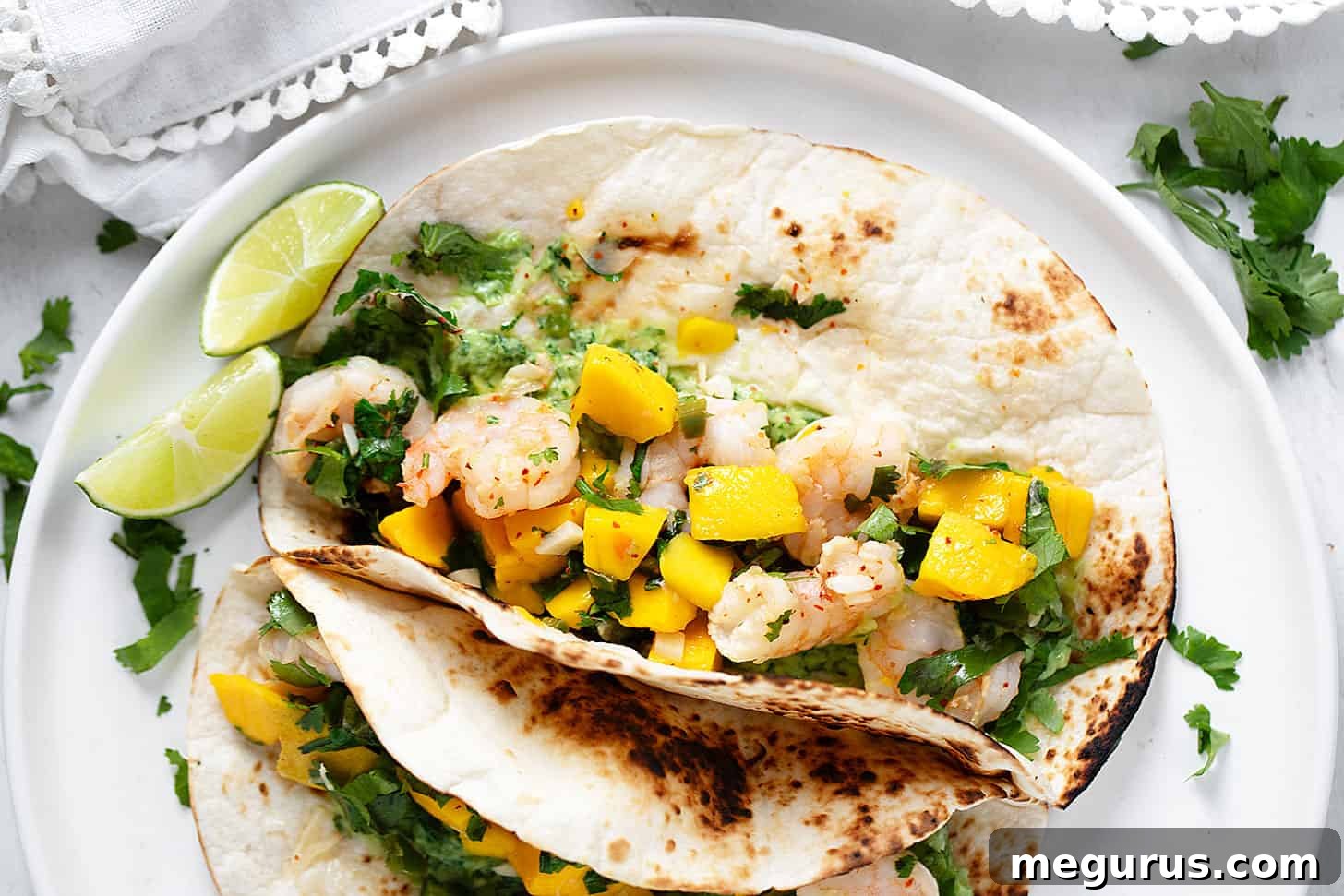 Delicious mango shrimp tacos artfully arranged on a serving plate, garnished with fresh cilantro and a lime wedge, ready to be enjoyed.