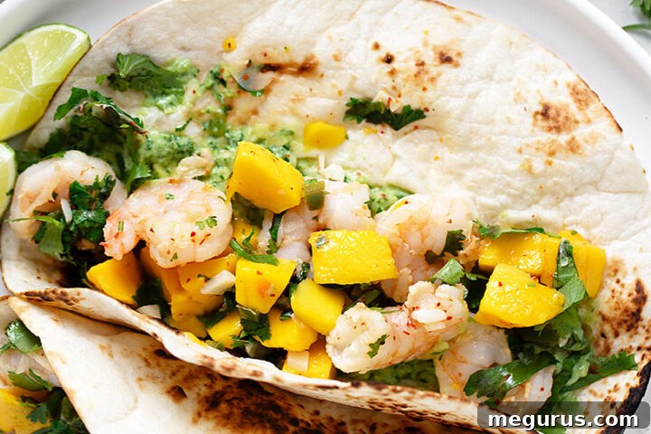 Shrimp tacos with mango on a serving plate.