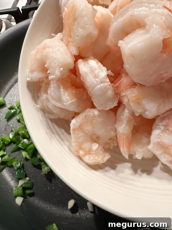Adding peeled and deveined shrimp to the sizzling skillet for a quick cook.