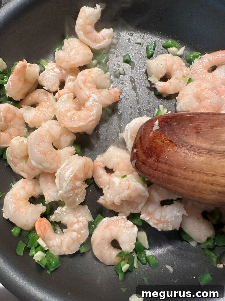 Shrimp, jalapeño, and garlic cooking together in a skillet, creating a fragrant blend.