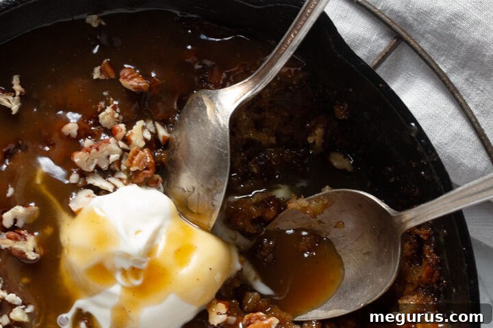 Apple sticky toffee pudding in a cast iron skillet with ice cream.