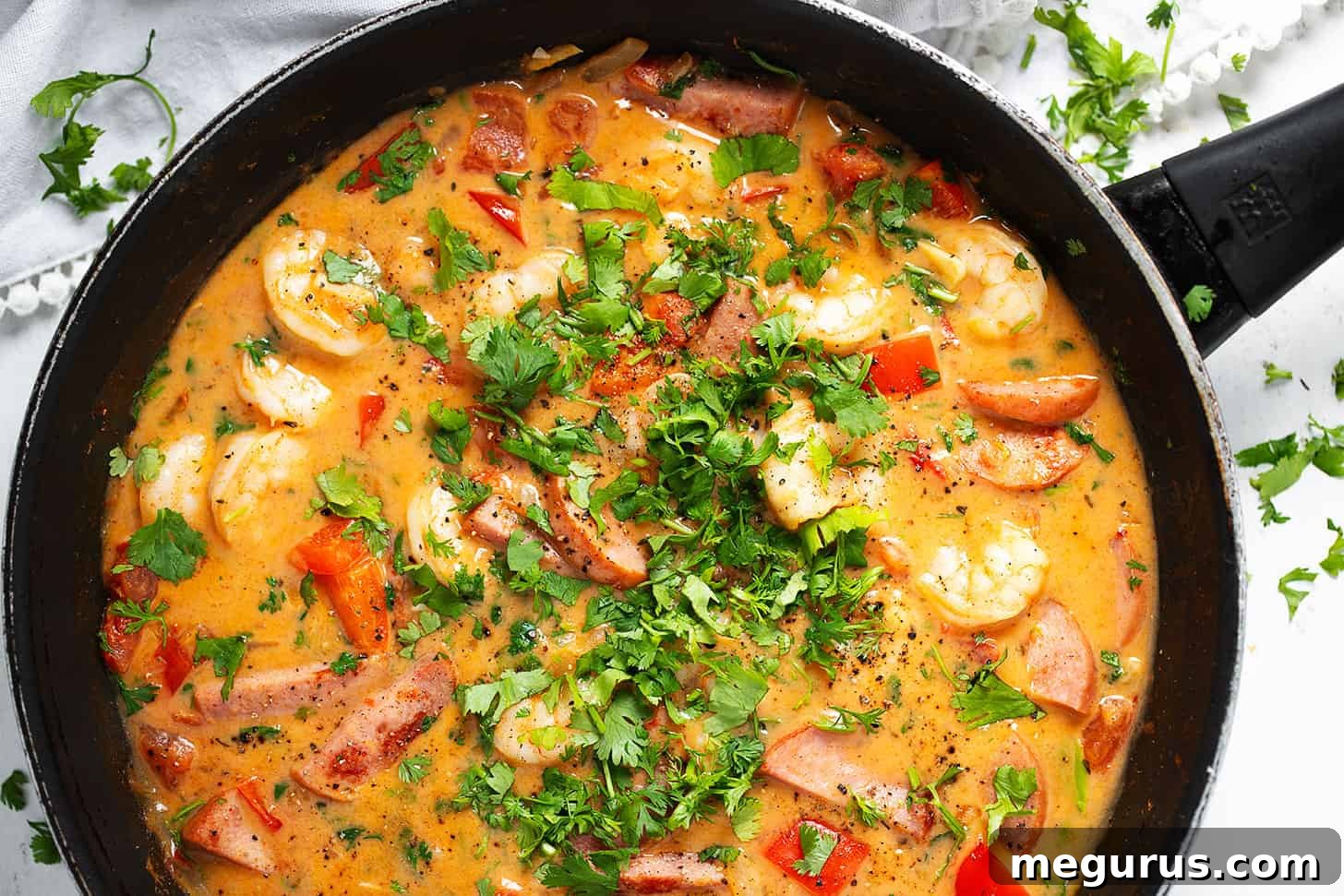 A vibrant, close-up shot of Cajun shrimp and sausage simmering in a skillet, garnished with fresh herbs, ready to be served.
