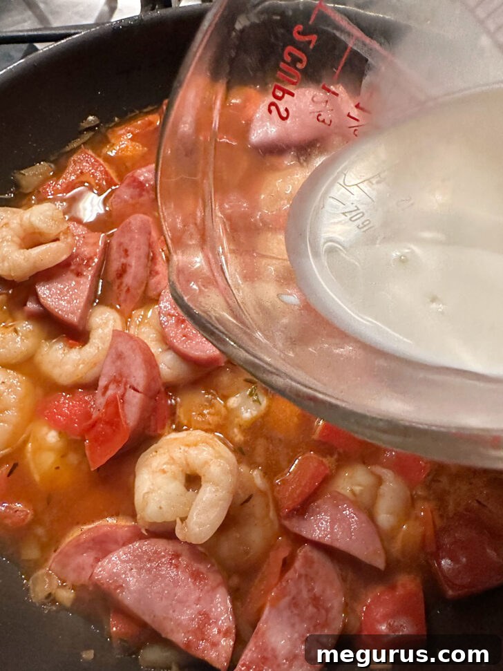 A splash of half and half cream being poured into the Cajun sauce, adding richness.
