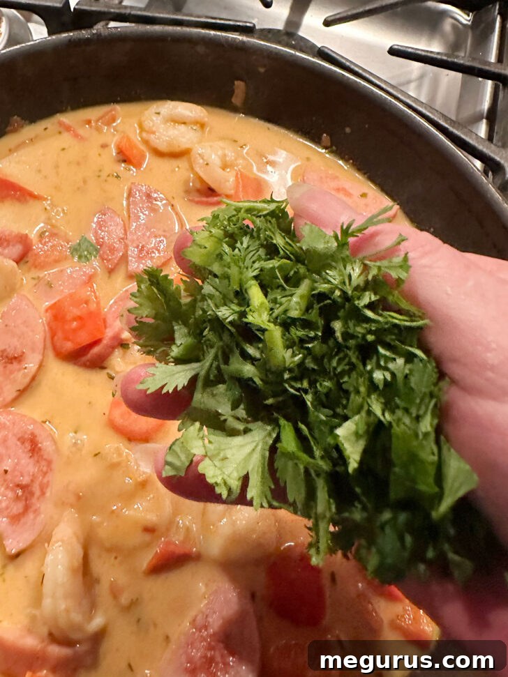 Freshly chopped parsley being sprinkled over the finished Cajun shrimp and sausage in the skillet.
