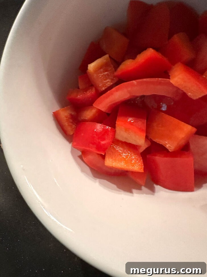 Diced fresh tomatoes and red bell pepper added to the skillet with spices and aromatics.
