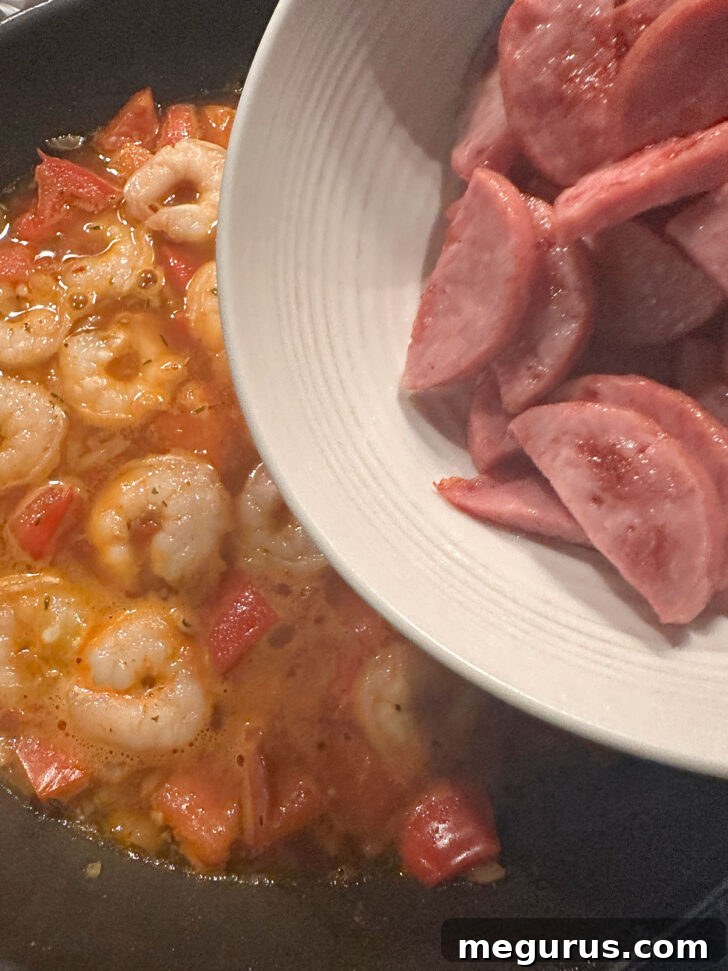 The browned Kielbasa sausage being returned to the skillet with the cooked shrimp and sauce.