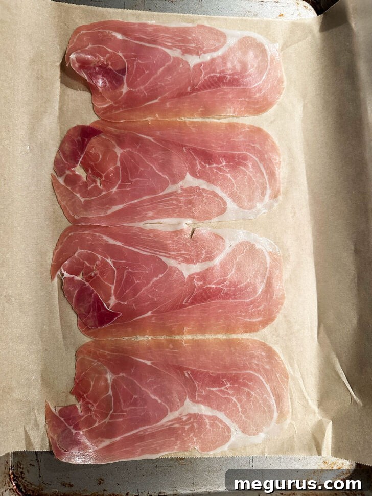 Prosciutto on parchment-lined baking sheet before cooking.
