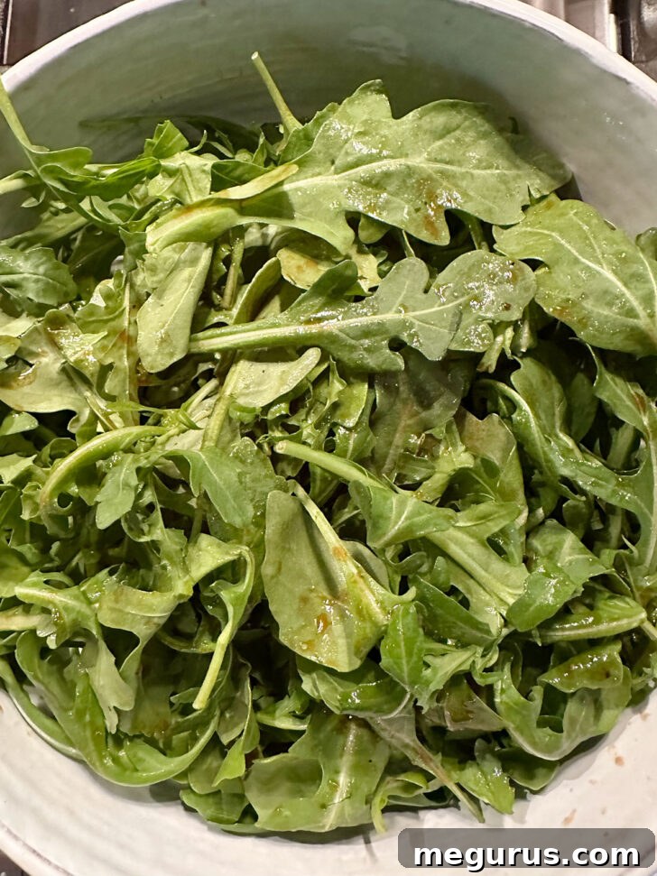 Arugula dressed with balsamic dressing in salad bowl.