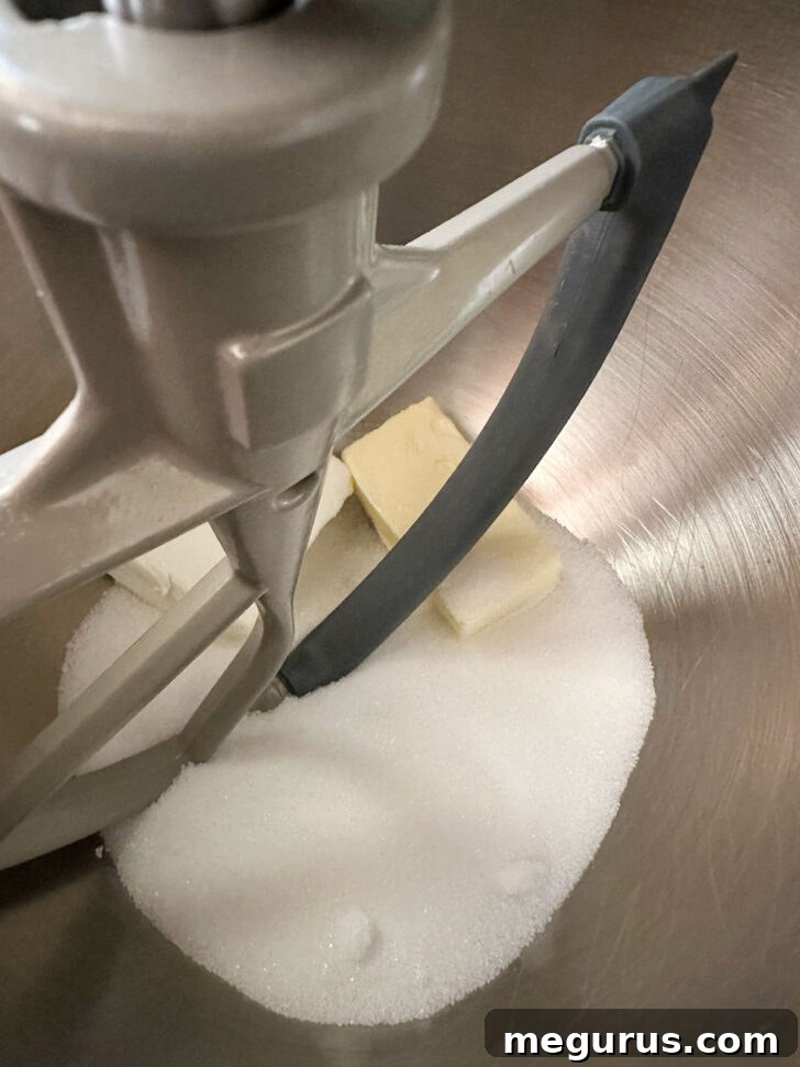 A large mixing bowl containing softened butter, granulated sugar, and cream cheese, ready to be creamed together for the cake batter.