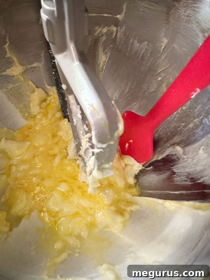 A spatula scraping down the sides of the mixing bowl, ensuring all ingredients are thoroughly incorporated into the cake batter.