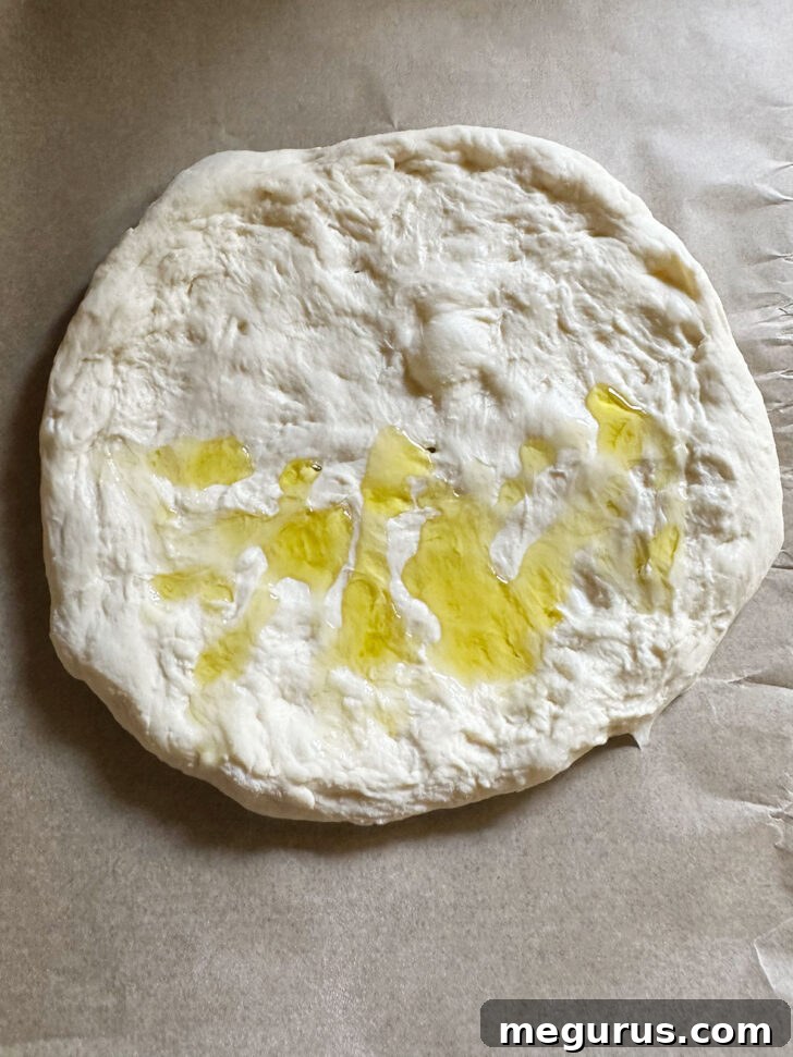 Olive oil drizzled over one half of the circular pizza dough, preparing it for folding.