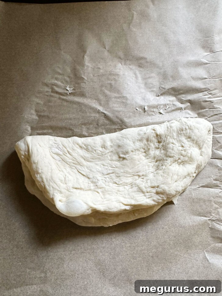 Pizza dough folded in half to create a half-moon shape, ready for baking.