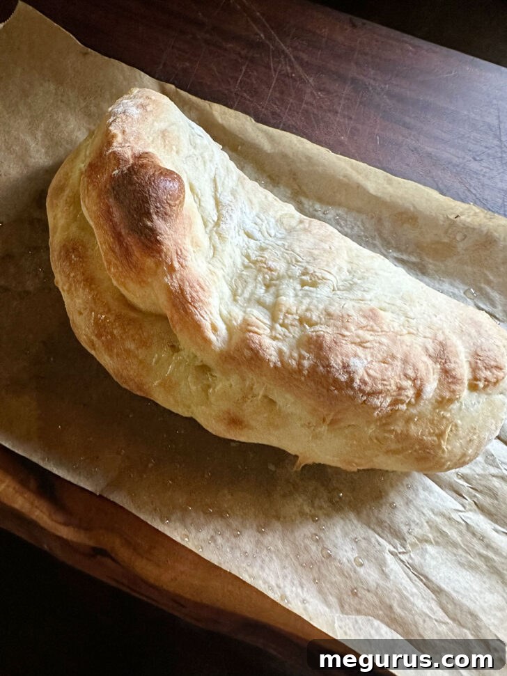 Baked pizza dough, golden and puffed, ready to be split open.