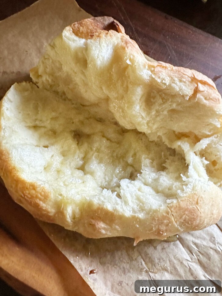 The baked pizza dough being carefully split open at its seam to create a pocket for fillings.