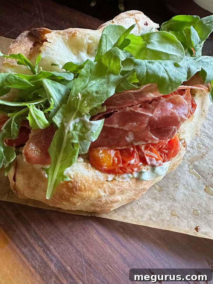 Fresh arugula leaves added as the final layer to the BLT pizza sandwich.