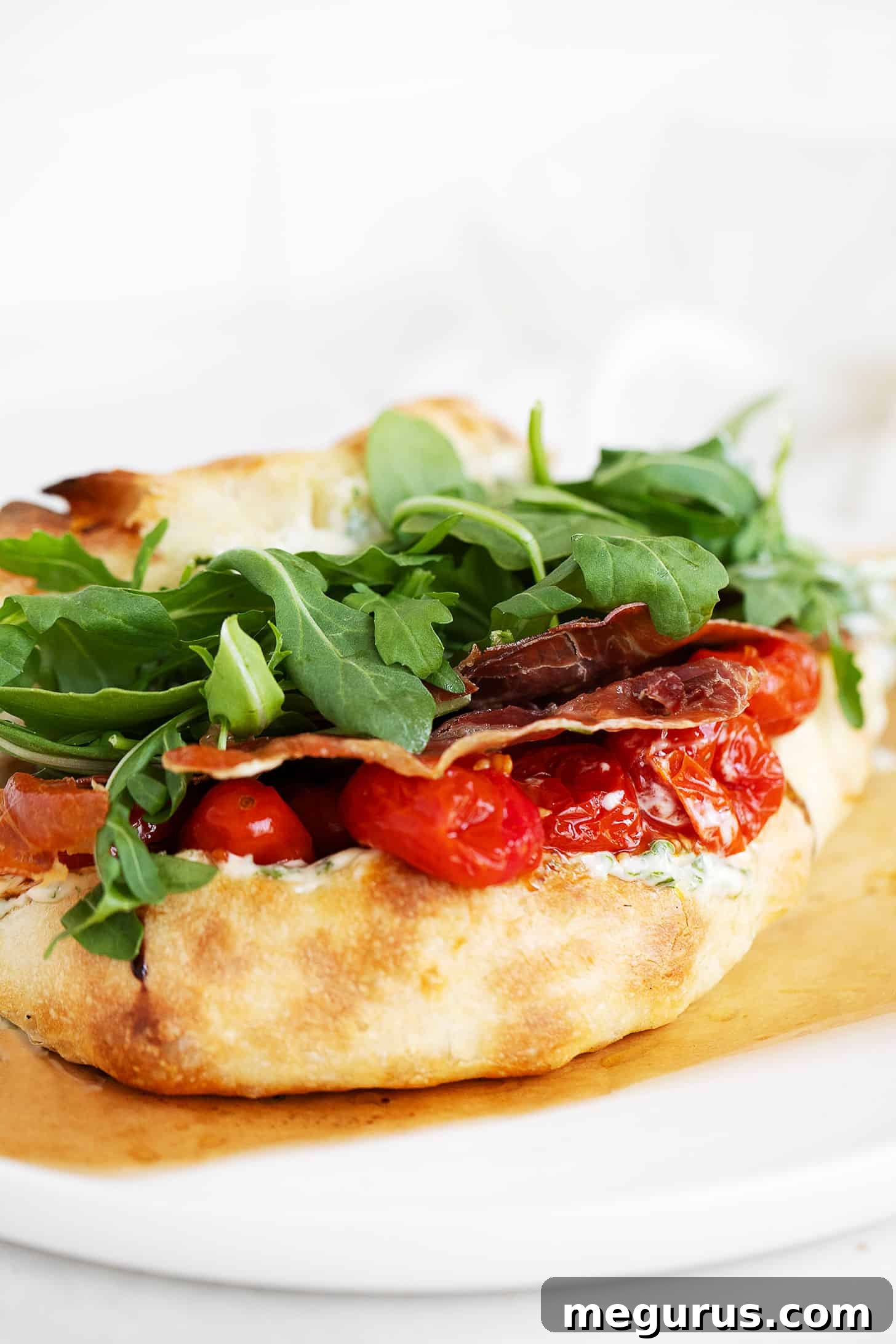 A close-up shot of the assembled BLT pizza sandwich, showing its layers of fresh ingredients and golden crust.