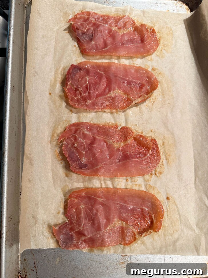 Crispy baked prosciutto slices removed from the oven, showcasing their perfect crunch.