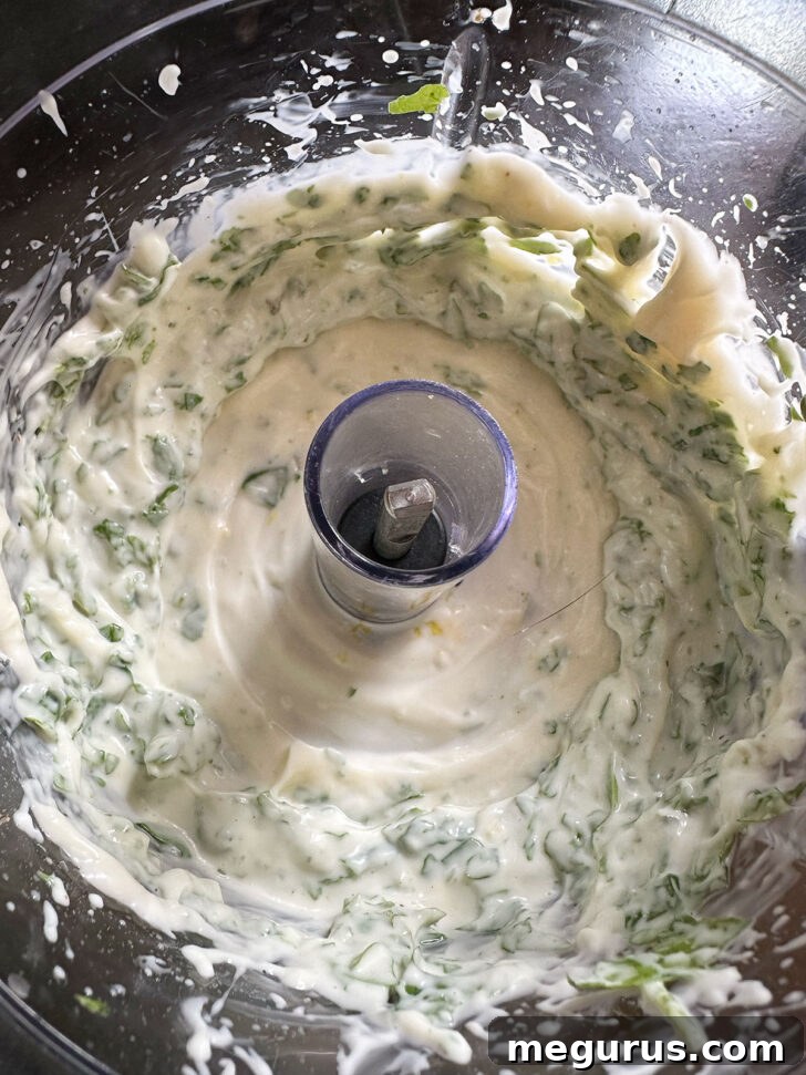 Smooth, vibrant green basil mayo after being processed, showcasing its creamy texture.