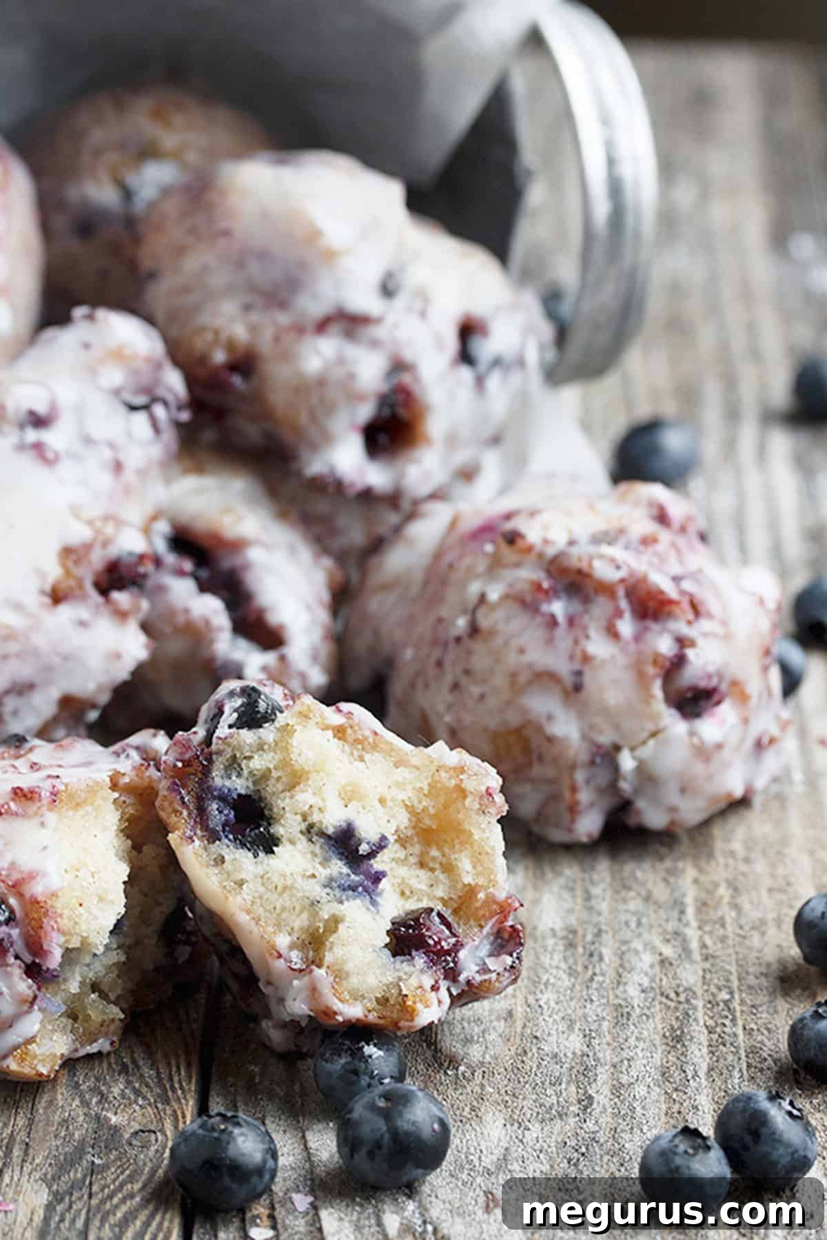 Freshly glazed blueberry fritters piled high in a rustic bucket
