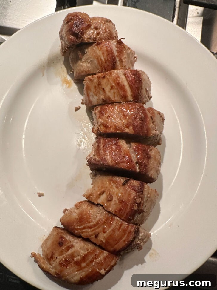 Pork medallions arranged neatly on a serving plate, awaiting the generous spooning of the warm, creamy mushroom Diane sauce.