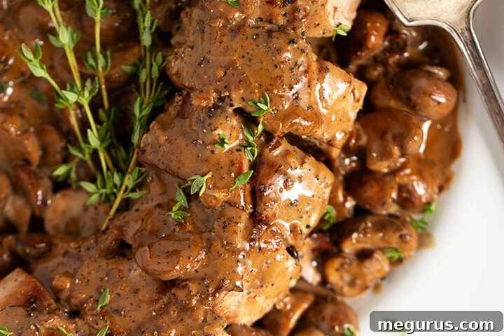 Pork tenderloin Diane on serving plate, showcasing the rich sauce.