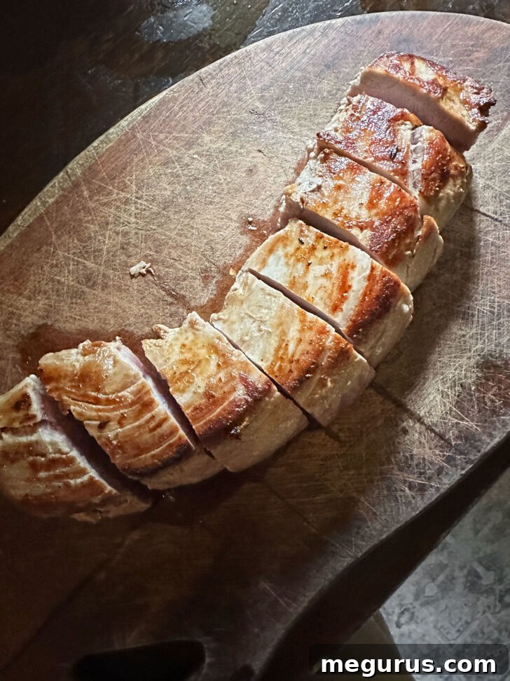 Browned pork tenderloin sliced into uniform medallions on a cutting board, ready for the next stage of cooking.