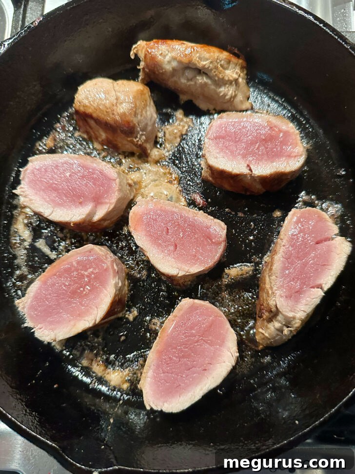 Pork medallions sizzling and browning in a hot skillet, developing a rich color.