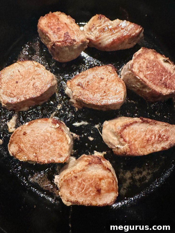 Flipping pork tenderloin medallions in a skillet to ensure even browning on all sides.
