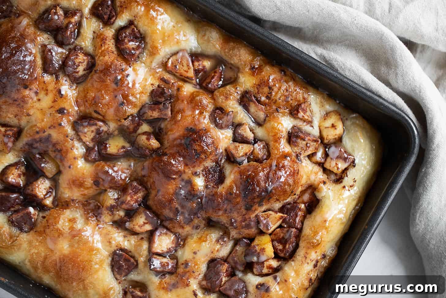 Freshly baked Apple Fritter Focaccia, golden brown and topped with cinnamon apples, in a rectangular baking pan.