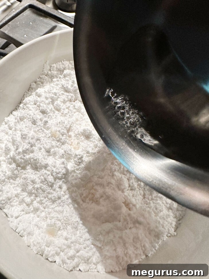 Hot sugar syrup mixture being poured into a bowl containing icing sugar, salt, and vanilla for the glaze.